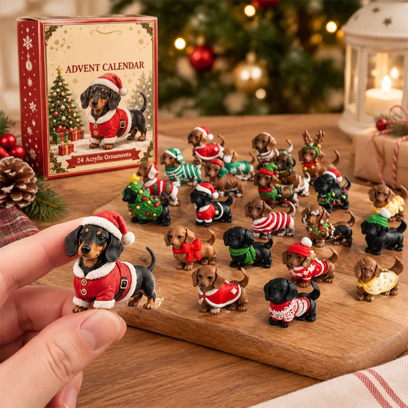 A hand holds a small dachshund figurine dressed in a Santa hat and coat, with a set of miniature dachshund Christmas ornaments arranged on a wooden board. The product box labeled 'ADVENT CALENDAR 24 Acrylic Ornaments' sits in the background on a holiday table with a tree and lantern.
