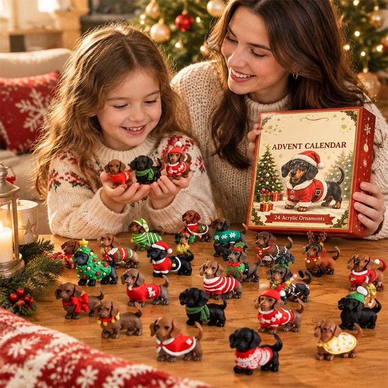 A woman and a young girl smile while looking at a box labeled 'Advent Calendar' filled with small dachshund dog ornaments wearing Christmas sweaters and hats. The scene is set on a wooden table with holiday decorations, a lit candle, and a Christmas tree in the background.